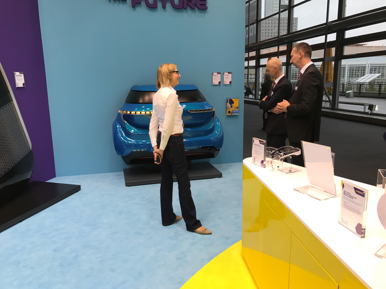 Merck in discussion with visitors of their booth at IAA in front of an OLED rear light demonstrator