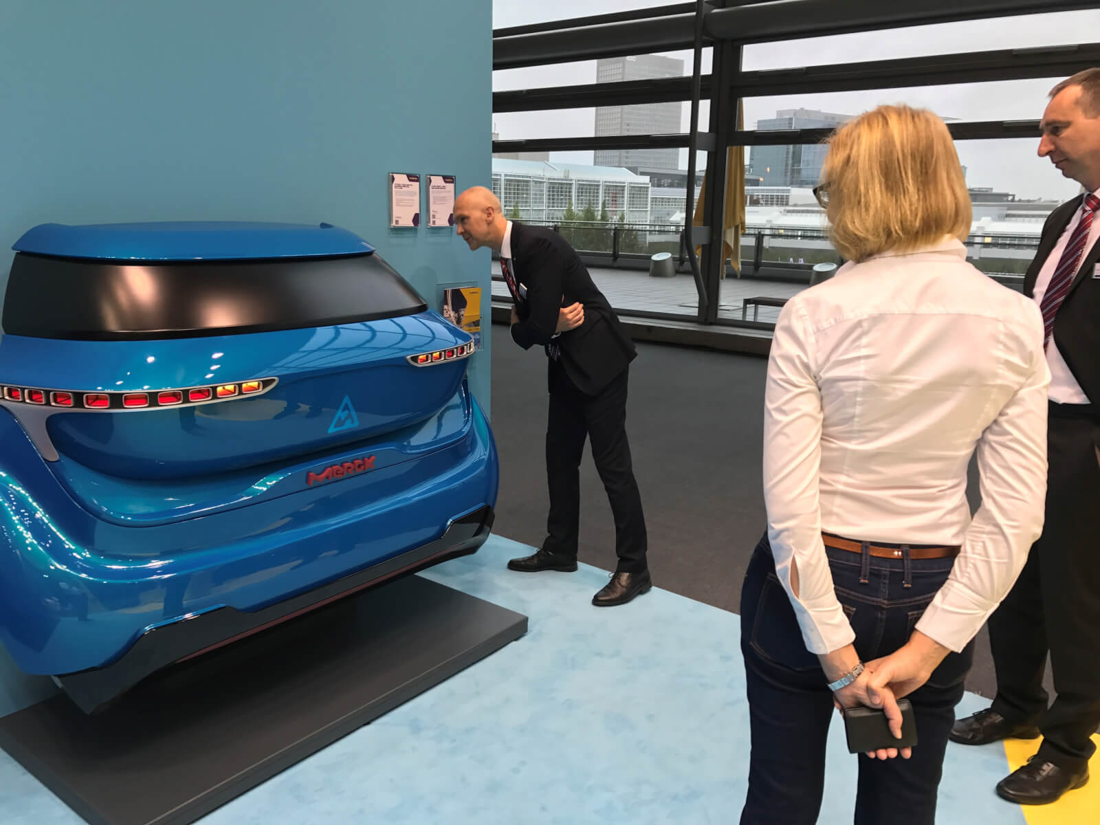 Man looking closer to the OLED rear light demonstrator at Merck booth at IAA